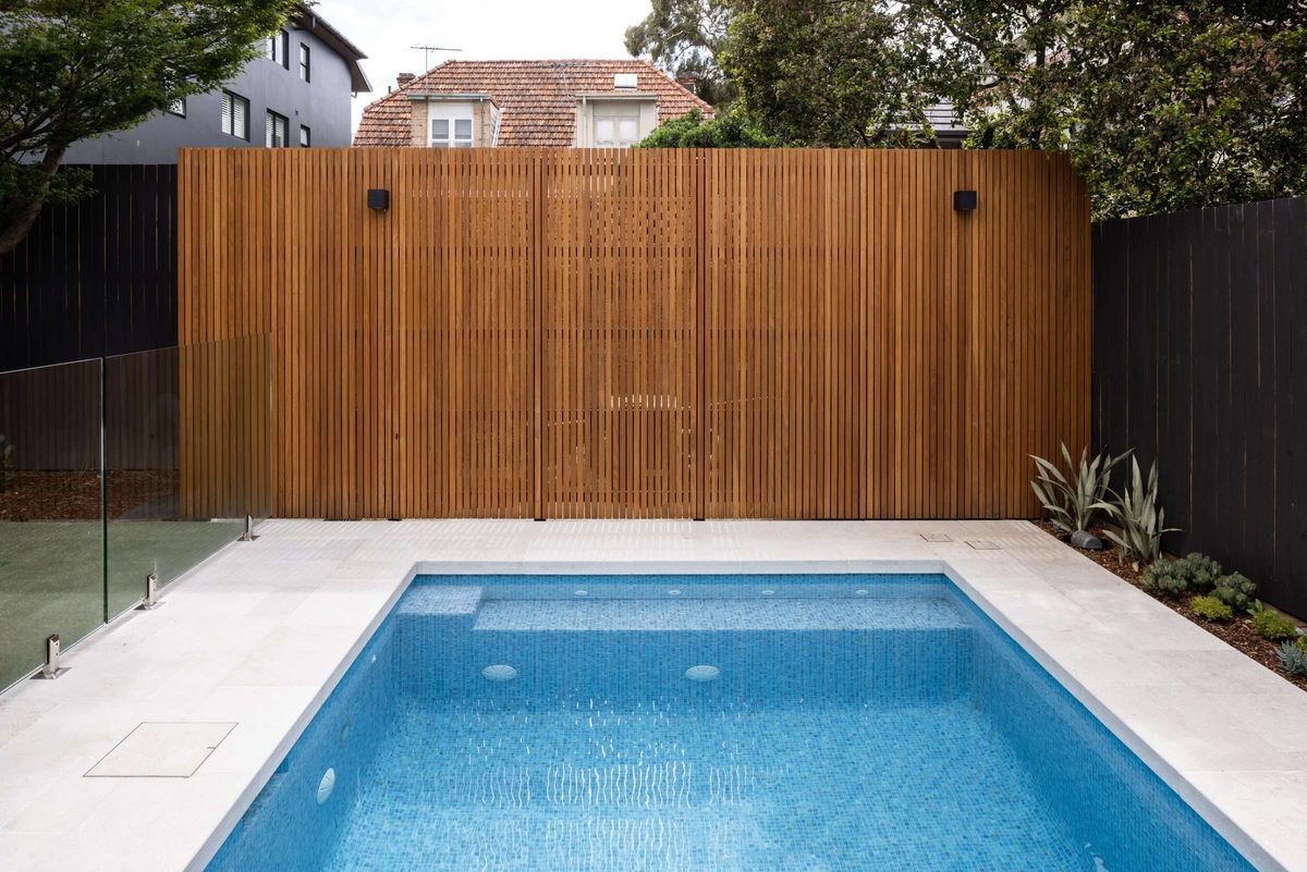 Mosaic-tiled pool, limestone surrounds and timber-battened privacy wall with glass fencing | Refined Group