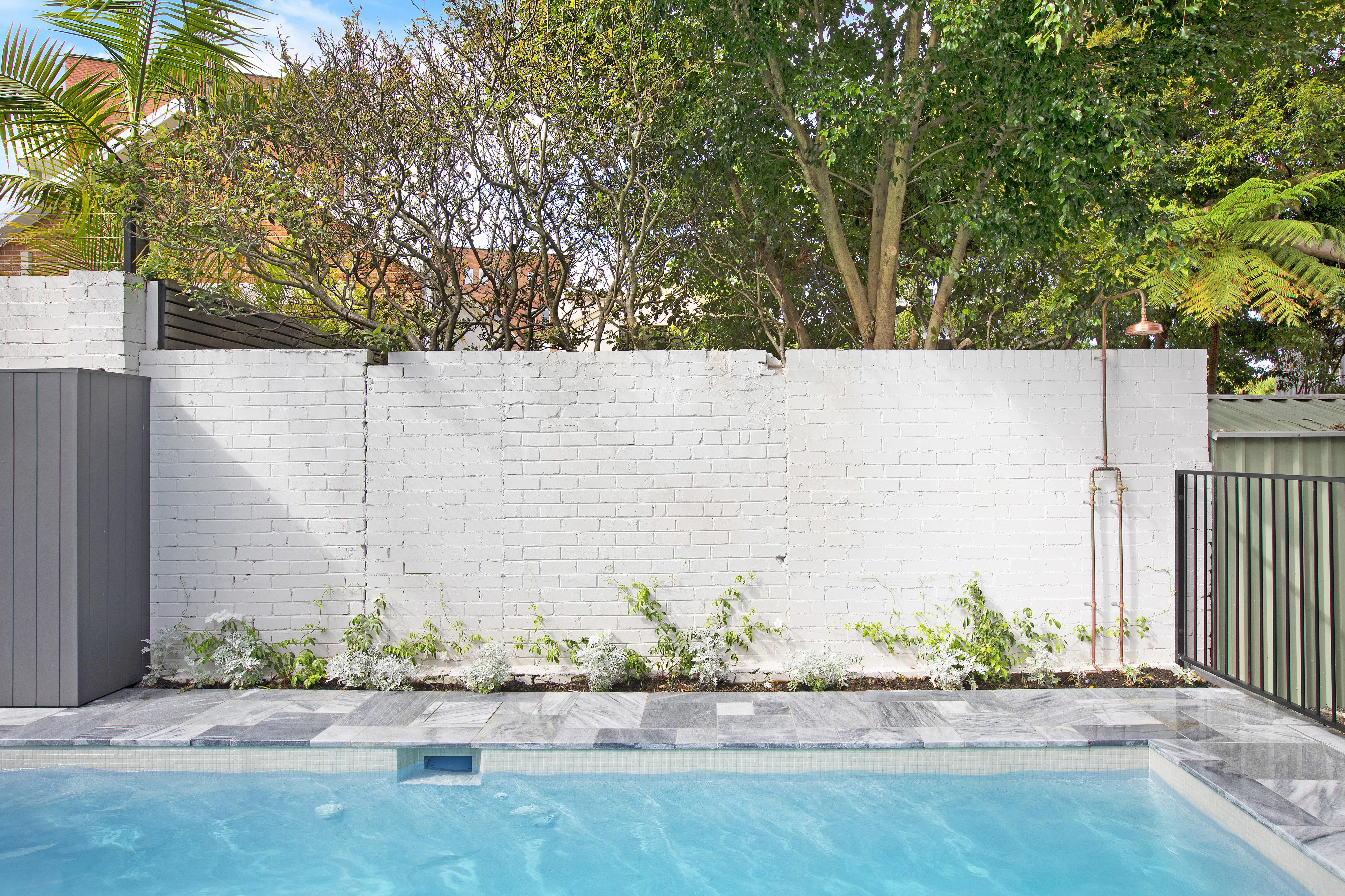 Mineral pool water against white painted brick with copper shower, Balmain