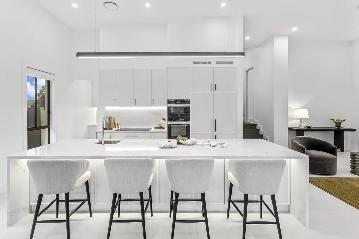 White kitchen with marble island bench and upholstered stools in a Refined Group custom home