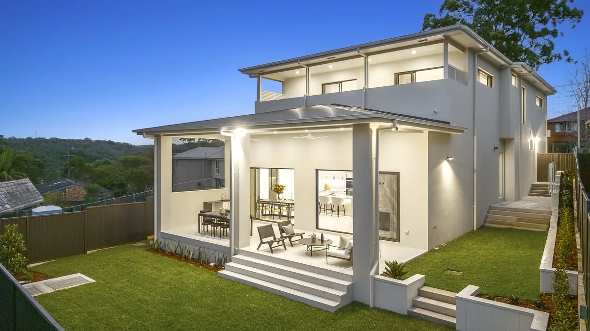 Custom home rear elevation at twilight: covered alfresco, lawn and bushland backdrop | Refined Group