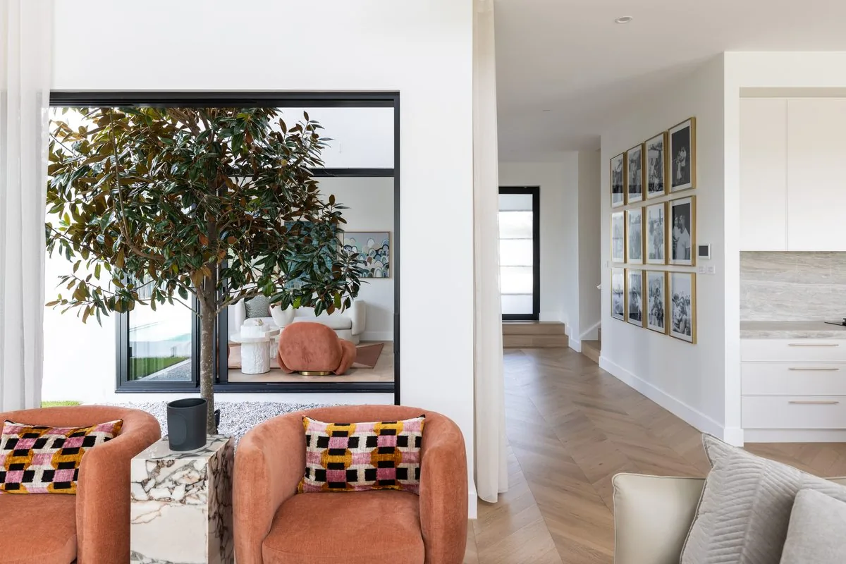 Living room opening to a garden courtyard and pool through glazed corner, Kellyville custom home by Refined Group