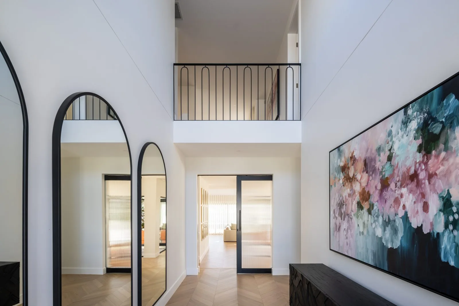 Double height entry void with arched mirrors and gallery balustrade, Refined Group custom home