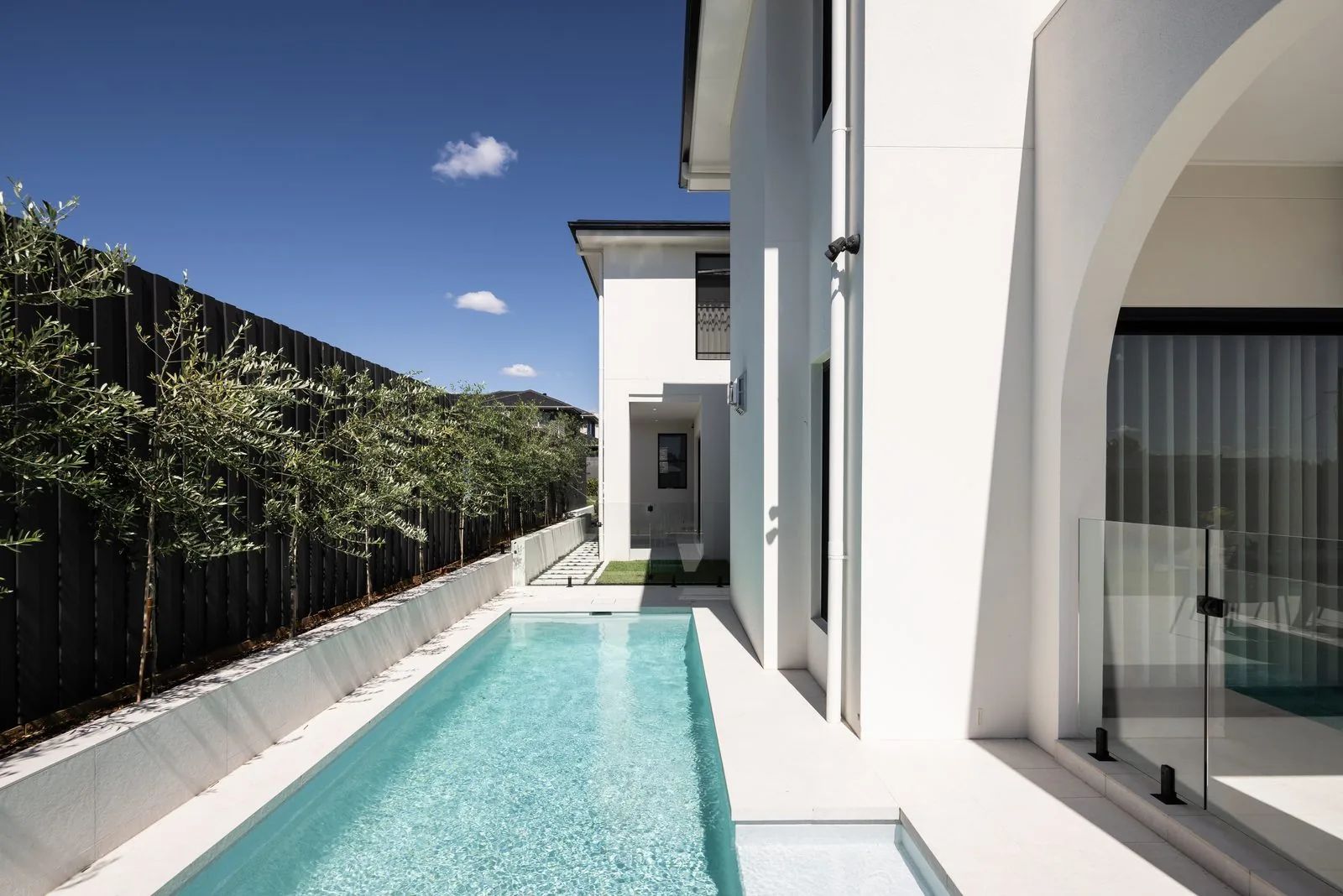 Lap pool with olive trees beside a Refined Group custom home