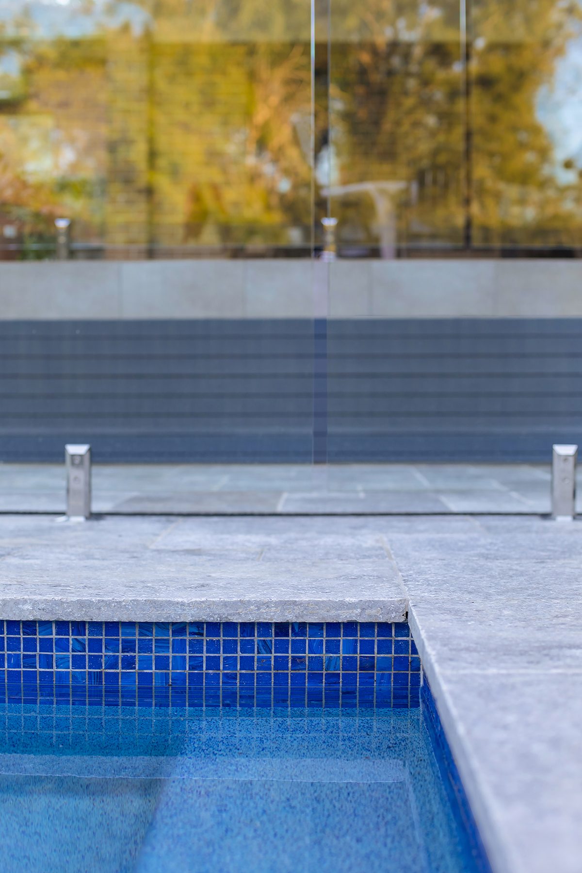 Mosaic waterline tiles and travertine coping. Detail of a Refined Group concrete pool, Pennant Hills