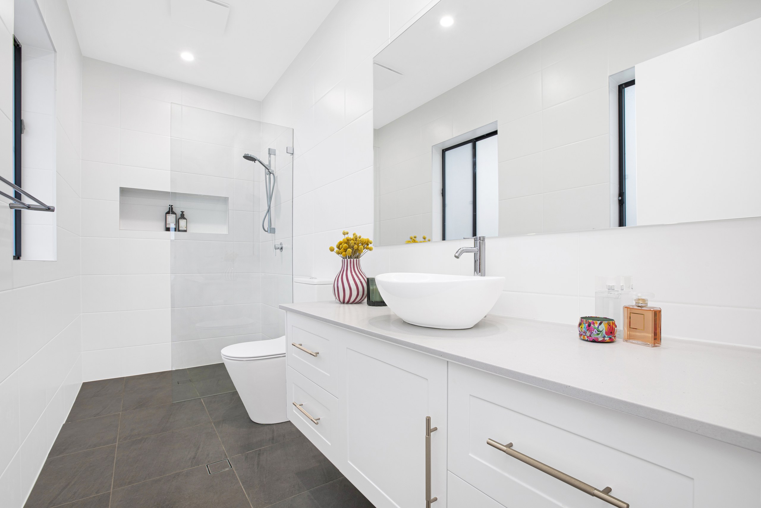 Main bathroom with stone floor tiles, twin windows and frameless shower, Seven Hills project
