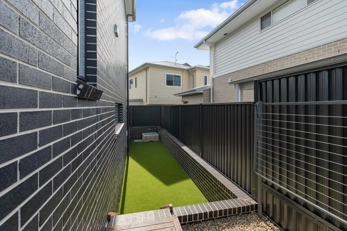 Turfed side yard, dark brick and new boundary fencing at a Refined Group project, Seven Hills