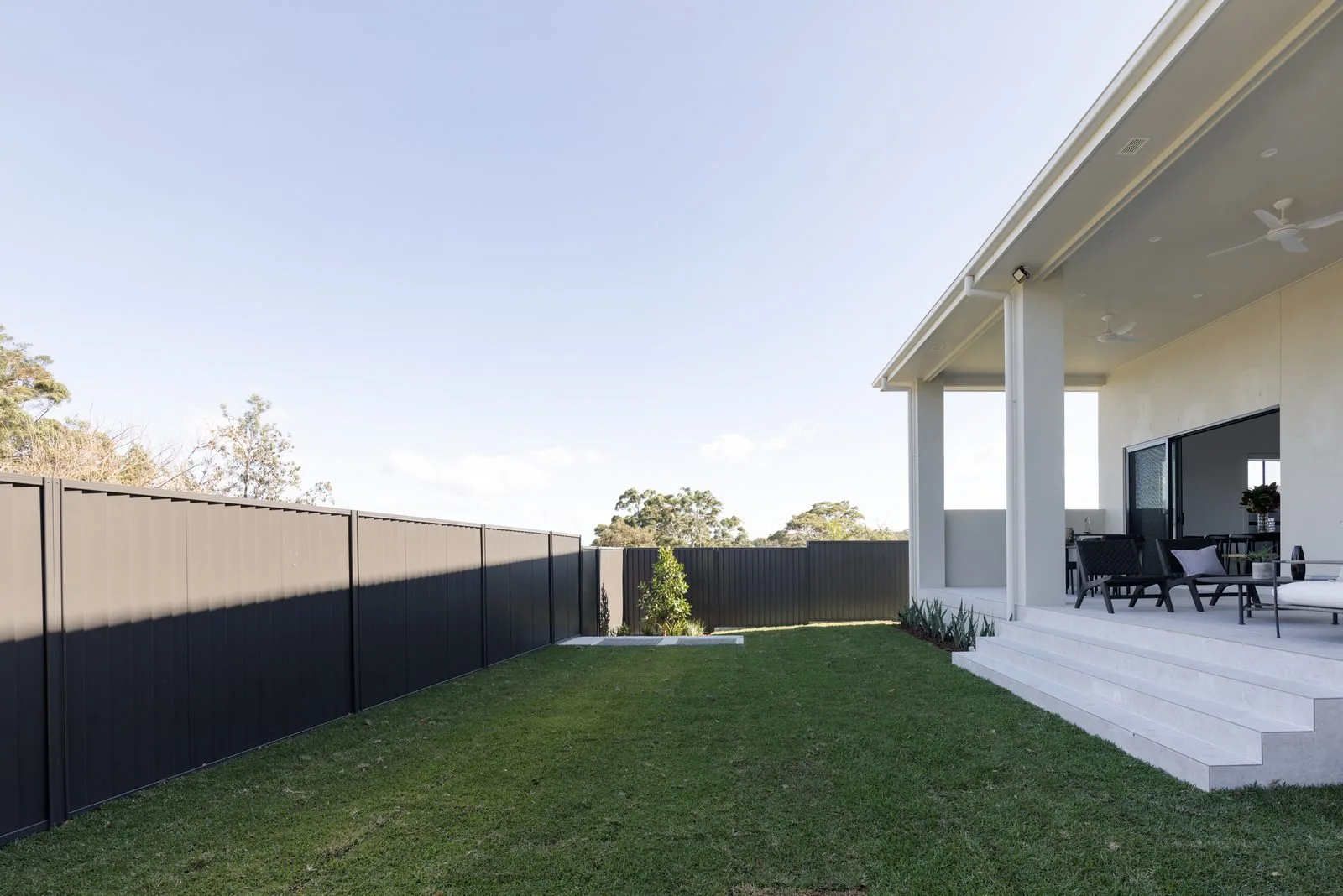 Level lawn and covered alfresco behind a Refined Group custom home