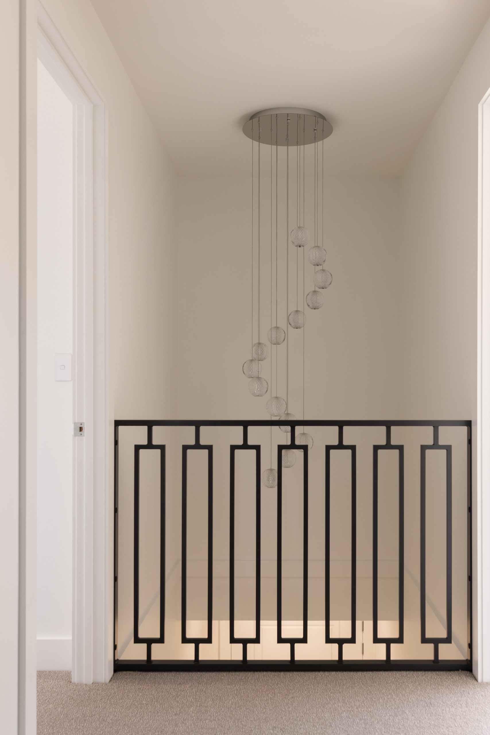 Stair void with pendant light and iron balustrade, Westleigh