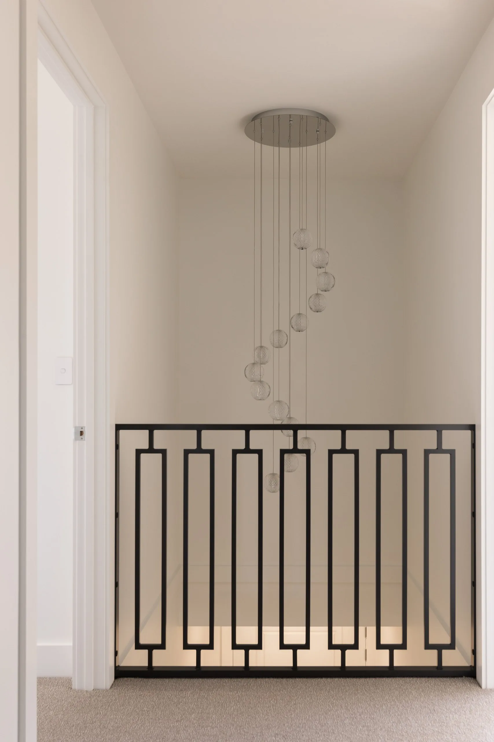 Stair void with pendant light and iron balustrade, Westleigh